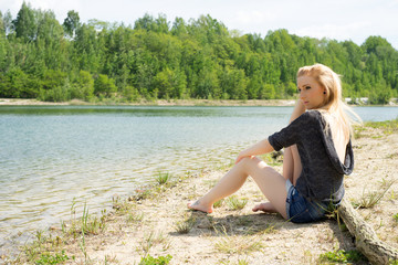 Fototapeta na wymiar Summer / pretty woman sitting in front of a lake