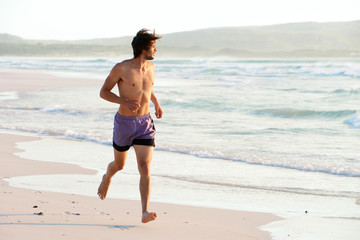 Fototapeta na wymiar Attractive man running shirtless at the beach