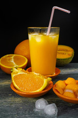 Glass with fresh ice cold pressed melon-orange juice and fresh fruit