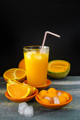 Glass with fresh ice cold pressed melon-orange juice and fresh fruit