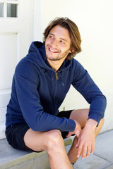 Smiling young man with beard sitting on patio