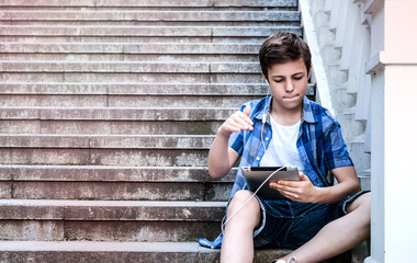 teenager with tablet sitting on the stairs