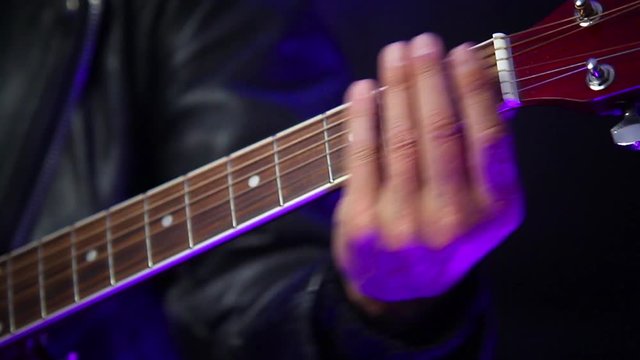 man's hand running over the strings of an acoustic guitar