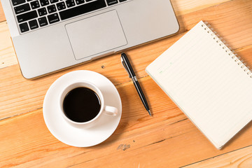 Spiral Notebook, pen and cup of coffee on laptop keyboard
