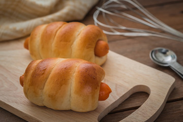 Bread rolls with sausage on wooden plate