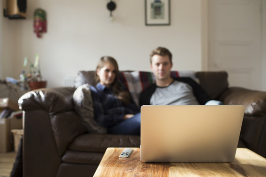 Young Couple Watching Movie Streamed To Laptop At Home