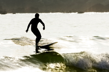 surfer man silhouette in solitary beach with  flat sea at sunset , selective focus
