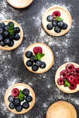Delicious tartlets with raspberries and blueberries on slate background
