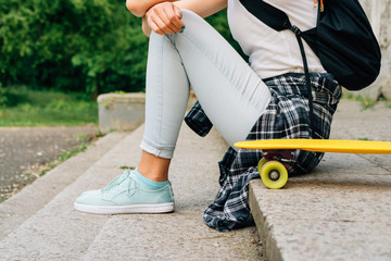 Obraz premium Teenager girl in jeans and a plaid shirt sitting on the steps ne