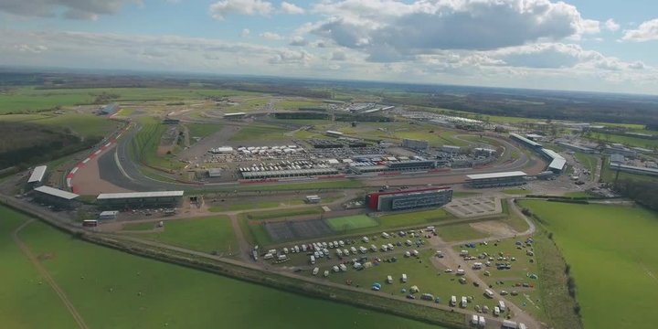 Aerial view of  a big  race on a sunny summer  day in England.  Cars going along the race. Full campsite.