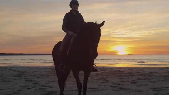 Silhouette of Rider on Horse at Beach in Sunset Light. Shot on RED Cinema Camera.