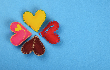 Four colorful felt craft art hearts on blue