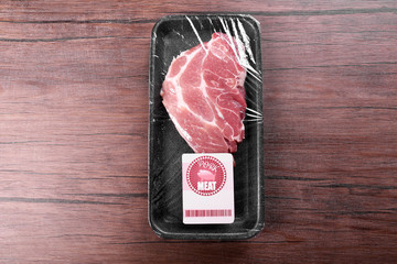 Packed piece of pork meat on wooden background