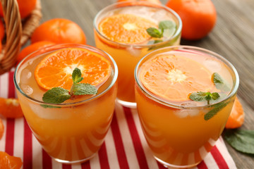 Delicious tangerine cocktails with sliced mandarins, ice and mint on a striped napkin, top view