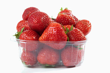 Erdbeeren im Plastikschälchen auf weissem Untergrund