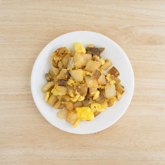 Breakfast meal on a white plate top view atop a wood table.