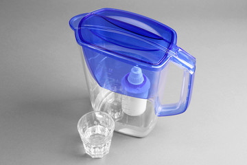 Water filter jug and a glass on the grey background