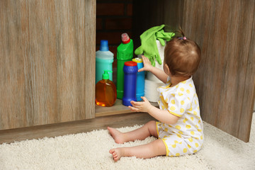 Little girl playing with detergents in kitchen