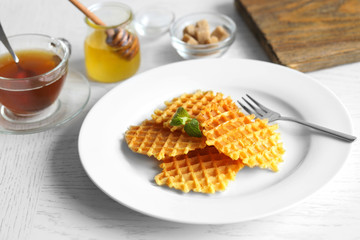 Tasty waffles with honey and mint on plate