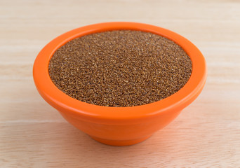 Teff grain filling a small bowl on wood table top