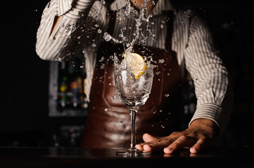 splash in a glass with lemon barman on background