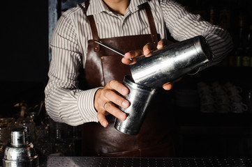 Barman makes cocktails with a shaker.