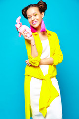 portrait of cheerful fashion hipster girl in casual colorful vivid hipster yellow summer clothes with toy in hands on blue background