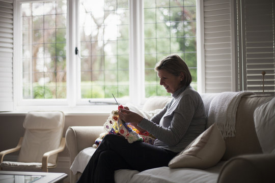 Woman sitting on sofa and knitting