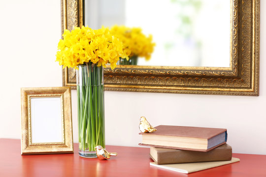 Beautiful bouquet of yellow narcissus on chest of drawers