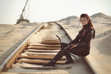 Raider girl in leather costume with a crossbow at post-apocalyptic world.