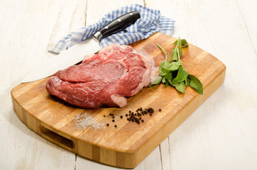 raw beef shoulder on wooden board with sage