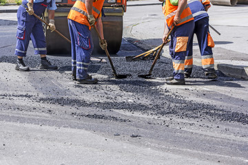 Roller and workers on asphalting and repair of city streets