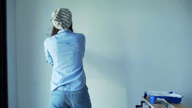 Unhappy, angry woman painting wall at her new home
