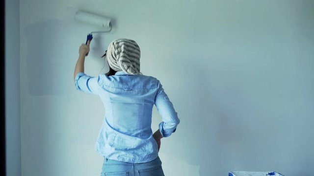 Unhappy, angry woman painting wall at her new home
