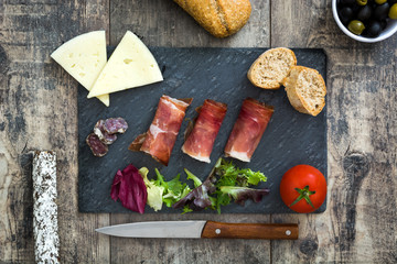 Spanish serrano ham, cheese and sausage on black slate
