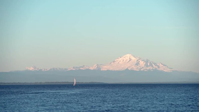 Mount Baker, Boundary Bay, Washington State. 4K UHD. A sailboat in Boundary Bay viewed from Point Roberts, Washington State. Mount Baker rises in the background.
  