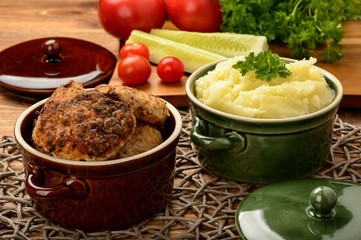 Meat cutlets and mashed potatoes in ceramic pots.