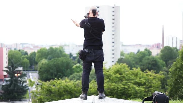 videomaker and photographer taking picture by the top of a park with city sight