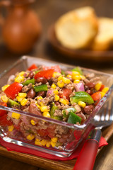 Chili con carne Salat aus Hackfleisch, rote Bohnen, Paprika, Tomate, Mais und Zwiebeln in Glasschüssel serviert (Selektiver Fokus, Fokus ein Drittel in den Salat)