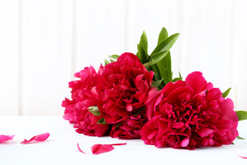 Bouquet of red peony flowers on a white wooden table