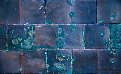 An old blue obsolete and damaged tiled wall