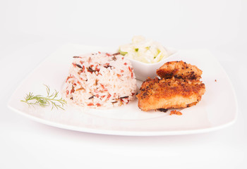 Pork chop (covered in breadcrumbs), three color rice and cucumber salad decorated with dill on a plate on white background