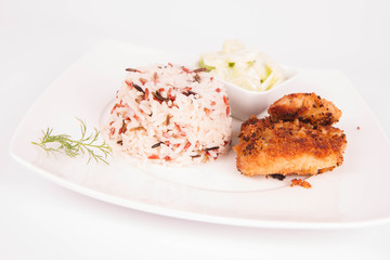 Pork chop (covered in breadcrumbs), three color rice and cucumber salad decorated with dill on a plate on white background