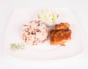 Pork chop (covered in breadcrumbs), three color rice and cucumber salad decorated with dill on a plate on white background