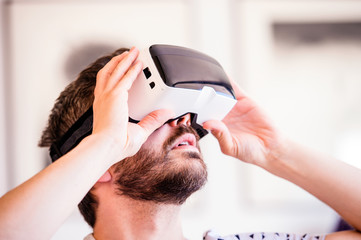 Naklejka premium Man wearing virtual reality goggles, sitting in living room