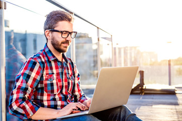 Businessman working from home on laptop, sitting on balcony