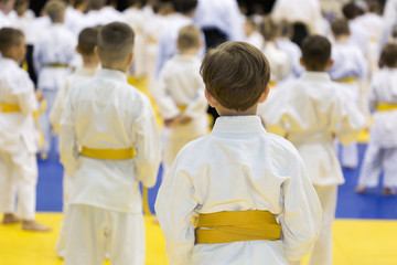 Fototapeta na wymiar Children in kimono sitting on tatami on martial arts seminar. Selective focus on a boy