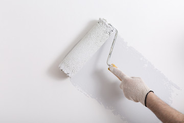 Close up of painter hand painting a wall grey with paint roller