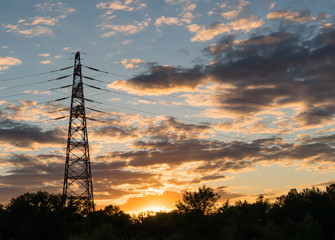 electricity transmission pylon at city suburb against the sunset glow sky.