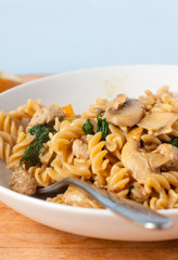 Sausage and mushroom pasta made with wholewheat fusilli in a white bowl